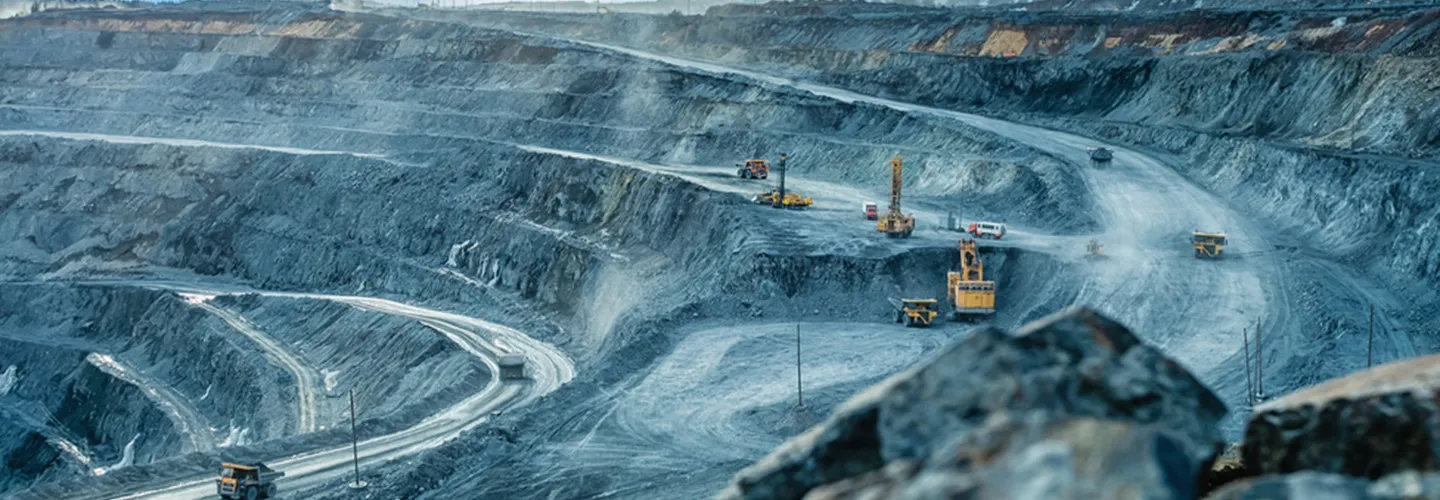 Large-scale open-pit mining operation featuring a massive yellow bucket-wheel excavator