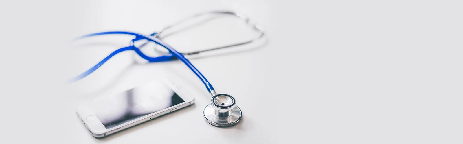 tethoscope placed next to a smartphone on a white surface, representing digital healthcare