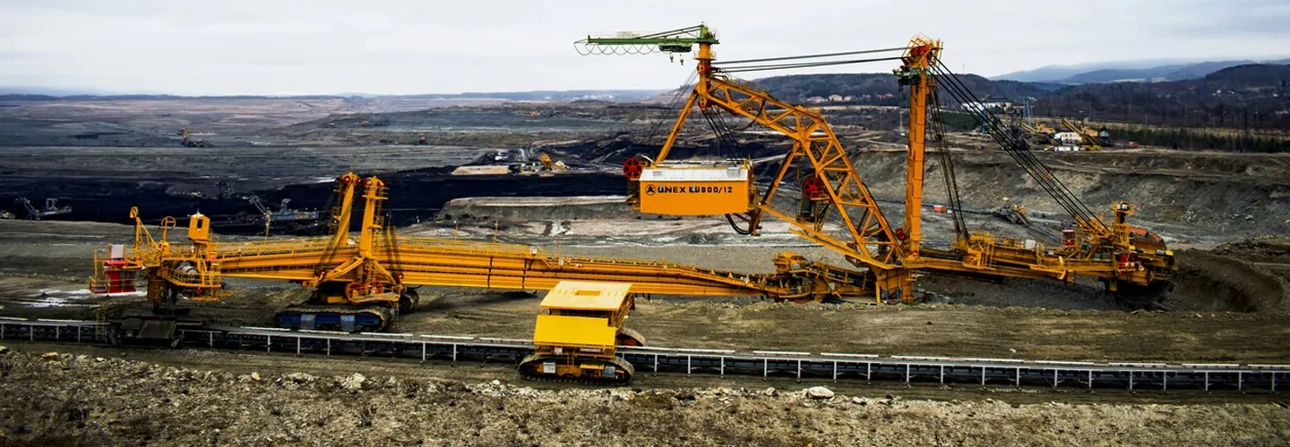 Large open-pit mining site with heavy machinery and trucks operating on multiple terraced levels